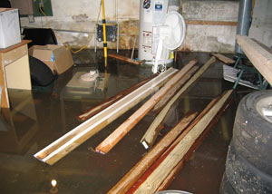 A severely flooding basement in Amherstburg, with lumber and personal items floating in a foot of water