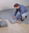Contractors installing basement subfloor tiles and matting on a concrete basement floor in Stratford, Ontario