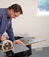 installing a waterproof vapor barrier on a basement floor to prepare for basement carpeting in a Chatham-Kent home